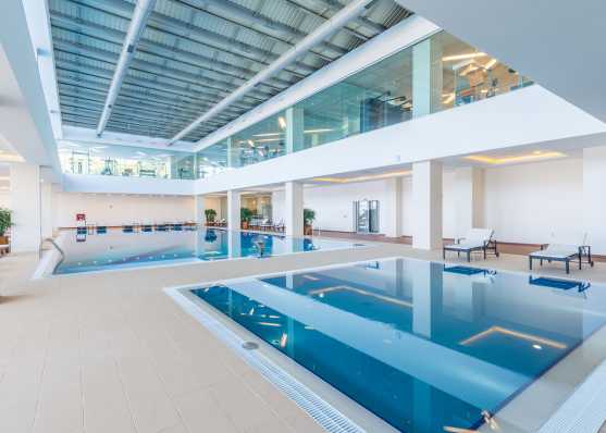 Weitläufiges Indoor-Swimmingpool mit Fitnessbereich im oberen Stockwerk