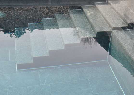 harmonisch eingebaute Schwimmbadtreppe Typ Milano mit Granitplatten ausgekleidet